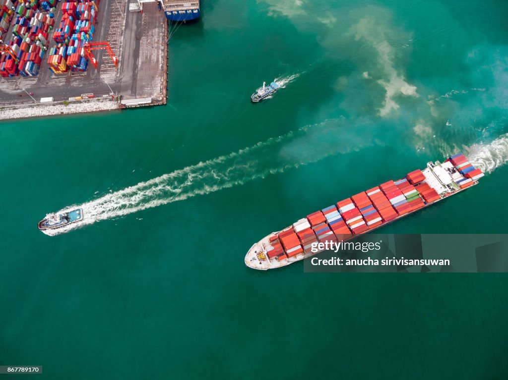 Two tug boat towing cargo container in warehouse harbor at thailand .