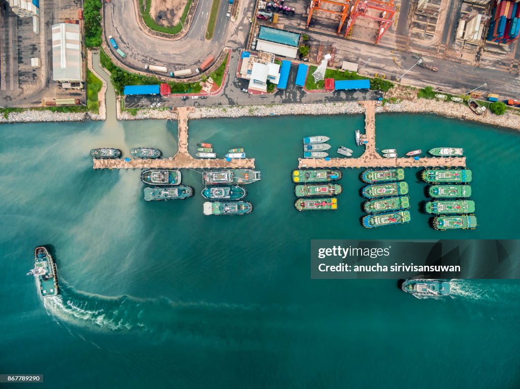 Two tug boat towing cargo container in warehouse harbor at thailand .