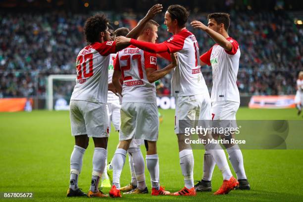 Alfred Finnbogason of Augsburg celebrates with his team-mates after scoring his team's second goal after penalty shot to make it 0-2 during the...