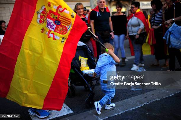 Child plays with a Spanish flag during a pro-unity demonstration on October 29, 2017 in Barcelona, Spain. Thousands of pro-unity protesters have...
