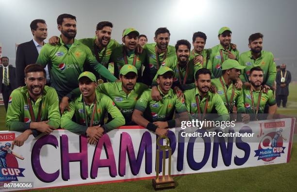 Pakistan's cricket team members pose for photographs with the trophy after winning the third and final T20 cricket match against Sri Lanka, at the...