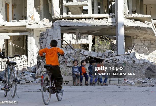 Syrian children sit outside a damaged building in the desert town of Al-Qaryatain on October 29 after regime forces retook it from Islamic State...