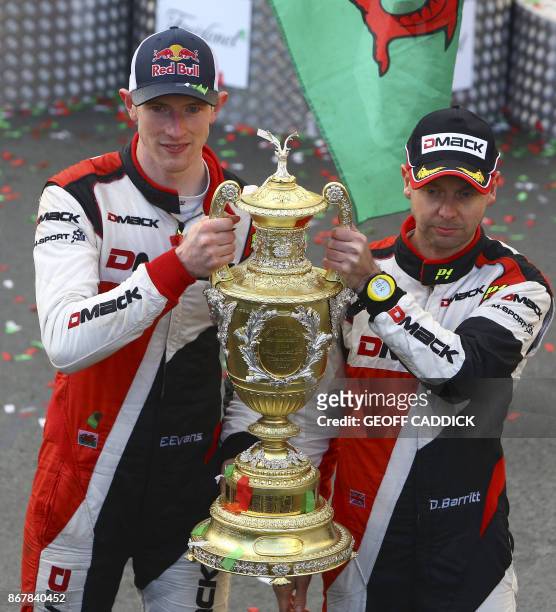 British pilot Elfyn Evans and co pilot Daniel Barritt of the M-Sport World Rally hold up their trophy as they celebrate after winning the 2017 Wales...