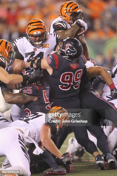 Jeremy Hill of the Cincinnati Bengals runs the football upfield against J.J. Watt of the Houston Texans during their game at Paul Brown Stadium on...