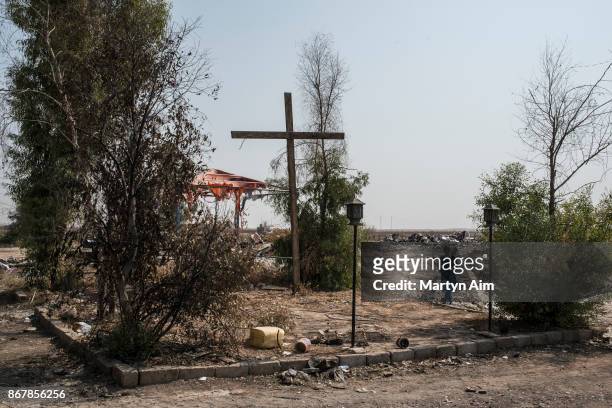 Girl stands under a wooden cross in the recently resettled Catholic town of Karemles, Iraq, on September 8, 2017.