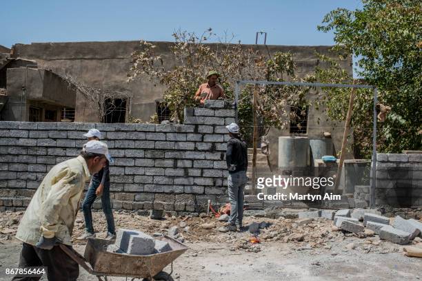 Catholic men work together to repair a family home damaged by Islamic State militants in Karamles, a Christian town in northern Iraq, on September 8,...
