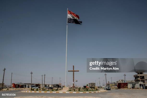 Tattered Iraqi flag flies above a cross in the Christian town of Qaraqosh in northern Iraq, on September 8, 2017.