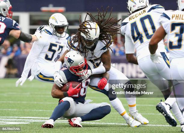 James White of the New England Patriots is tackled by of the Tre Boston of the Los Angeles Chargers during the first quarter of a game at Gillette...