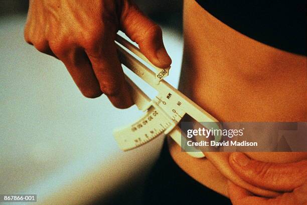 woman using skin fold caliper to measure body fat, close-up - skin fold calliper - fotografias e filmes do acervo