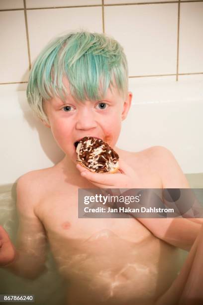 littel boy eating ice cream in bath tub - eis baden stock-fotos und bilder