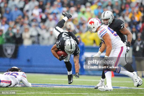 DeAndre Washington of the Oakland Raiders runs with the ball as Matt Milano of the Buffalo Bills attempts to tackle him during the first quarter of...