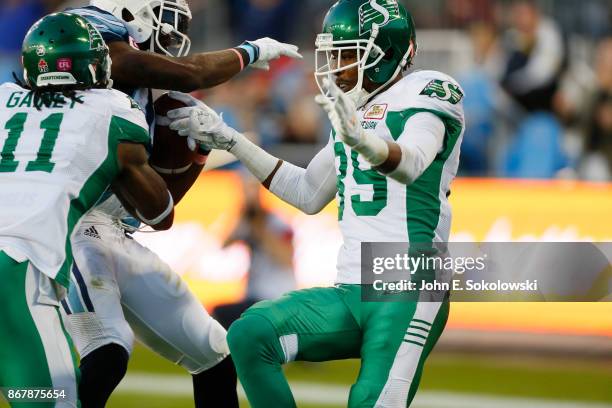 Duron Carter of the Saskatchewan Roughriders comes in to help Ed Gainey of the Saskatchewan Roughriders on stopping S.J. Green of the Toronto...