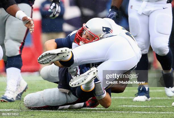 Tom Brady of the New England Patriots is tackled by Desmond King of the Los Angeles Chargers during the third quarter of a game at Gillette Stadium...