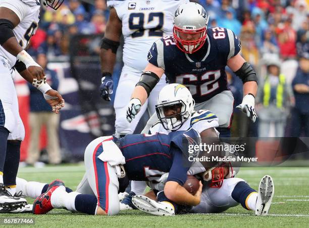 Tom Brady of the New England Patriots is tackled by Desmond King of the Los Angeles Chargers during the third quarter of a game at Gillette Stadium...