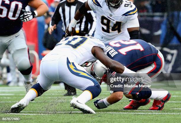 Tom Brady of the New England Patriots is tackled by Desmond King of the Los Angeles Chargers during the third quarter of a game at Gillette Stadium...