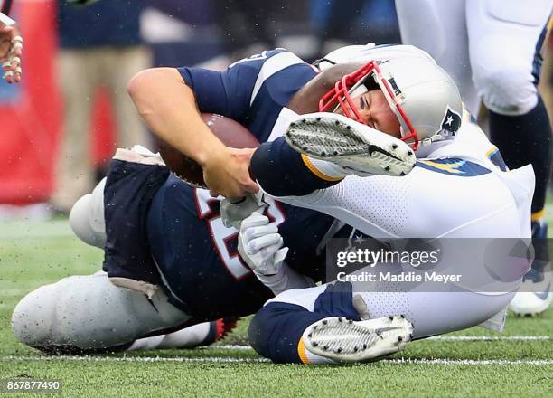 Tom Brady of the New England Patriots is tackled by Desmond King of the Los Angeles Chargers during the third quarter of a game at Gillette Stadium...