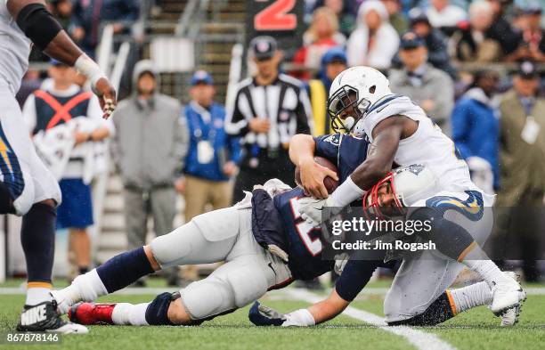 Tom Brady of the New England Patriots is tackled by Desmond King of the Los Angeles Chargers during the third quarter of a game at Gillette Stadium...