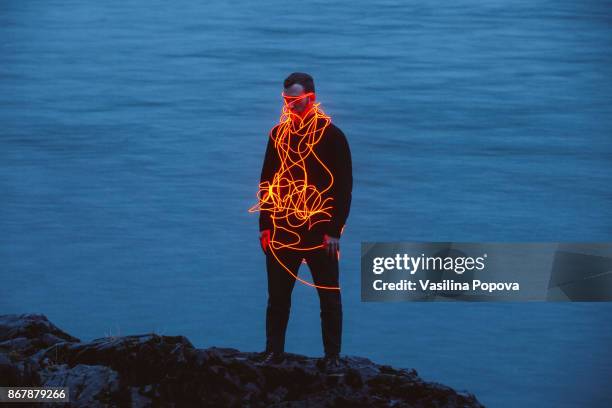 Man entangled with neon wires against nature background