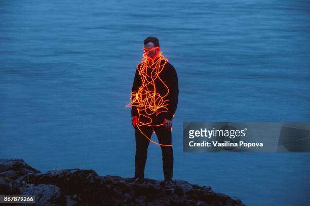 man entangled with neon wires against nature background - anonymous silhouette stock pictures, royalty-free photos & images