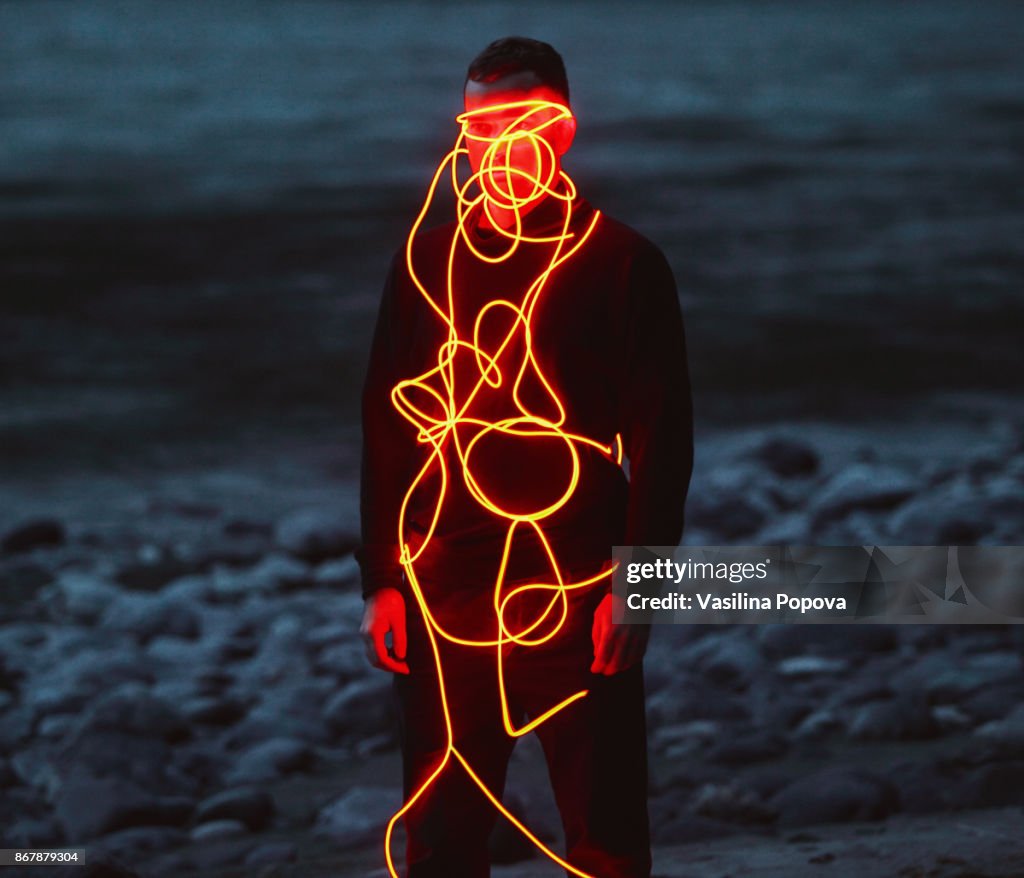 Man entangled with neon wires against nature background