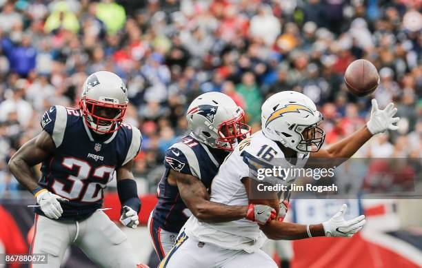 Tyrell Williams of the Los Angeles Chargers catches a pass as he is defended by Jonathan Jones and Devin McCourty of the New England Patriots during...