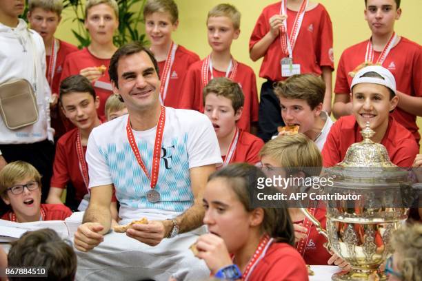 Switzerland's Roger Federer eats pizza with ball kids after defeating Argentina's Juan Martin del Potro in their final match in the Swiss Indoors ATP...