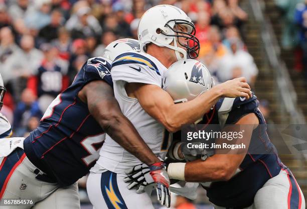 Philip Rivers of the Los Angeles Chargers is tackled by David Harris and Lawrence Guy of the New England Patriots during the fourth quarter of a game...