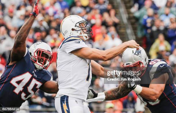 Philip Rivers of the Los Angeles Chargers is tackled by David Harris and Lawrence Guy of the New England Patriots during the fourth quarter of a game...