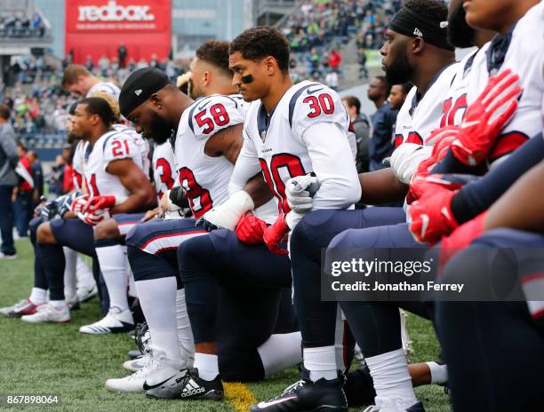 Members of the Houston Texans, including Kevin Johnson and Lamarr Houston, kneel during the national anthem before the game at CenturyLink Field on...