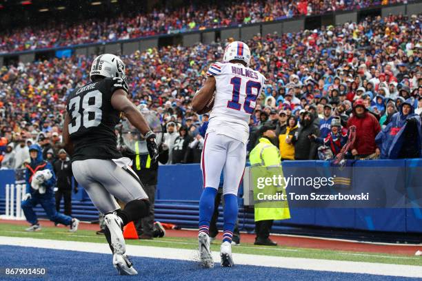 Andre Holmes of the Buffalo Bills drags his feet to score a touchdown as T.J. Carrie of the Oakland Raiders attempts to defend him during the second...