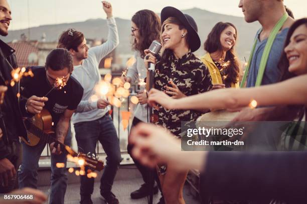 friends celebrating new year on rooftop party - christmas singing stock pictures, royalty-free photos & images