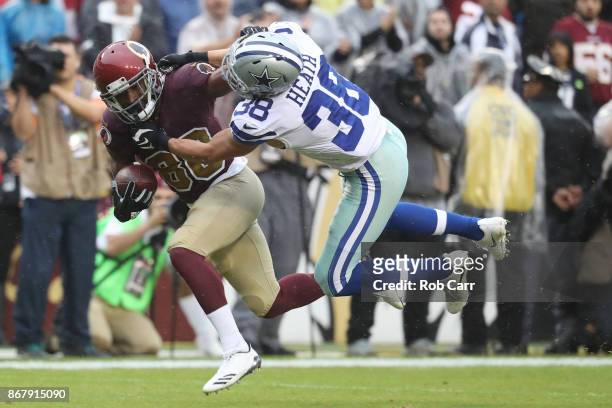 Wide receiver Jamison Crowder of the Washington Redskins stiff arms strong safety Jeff Heath of the Dallas Cowboys during the first quarter at FedEx...