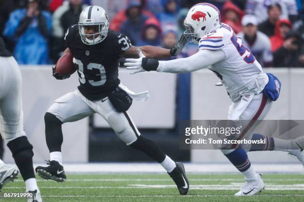 DeAndre Washington of the Oakland Raiders runs the ball as Ryan Davis of the Buffalo Bills attempts to tackle him during the second quarter of an NFL...