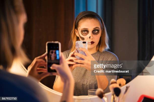 young woman sharing her halloween makeup on social media - backstage mirror stock pictures, royalty-free photos & images