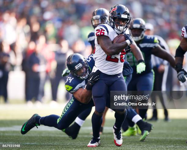 Running back Lamar Miller of the Houston Texans breaks a tackle by middle linebacker Bobby Wagner of the Seattle Seahawks during the third quarter of...
