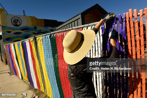 Volunteer Jaima Peterson helps to work on a new colorful fence to protect the tiny homes at the Beloved Community Village in the RiNo Art District at...