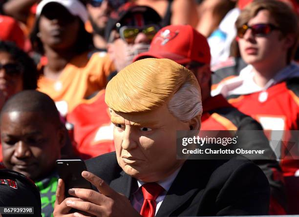 Fan dressed as President Donald Trump keeps his fingers moving on his iPhone during the Carolina Panthers against Tampa Bay Buccaneers game on...