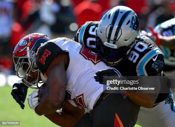 Carolina Panthers defensive end Julius Peppers, right, makes the tackle on Tampa Bay Buccaneers running back Doug Martin, left, during fourth quarter...