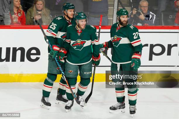 Jonas Brodin, Luke Kunin and Kyle Quincey of the Minnesota Wild celebrate after scoring a goal against the New York Islanders during the game at the...