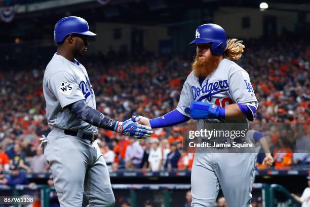 Justin Turner of the Los Angeles Dodgers celebrates scoring on a RBI single during the first inning with Yasiel Puig against the Houston Astros in...