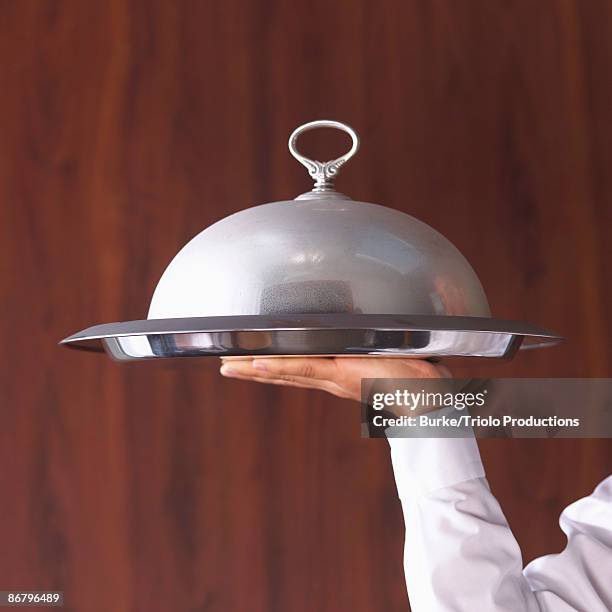 waiter's hand holding domed serving tray - vassoio da portata foto e immagini stock