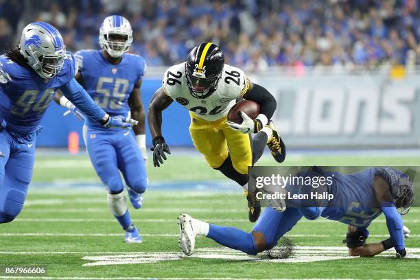 Le'Veon Bell of the Pittsburgh Steelers goes airborne over Detroit defenders Ezekiel Ansah of the Detroit Lions, Tahir Whitehead and Tavon Wilson of...