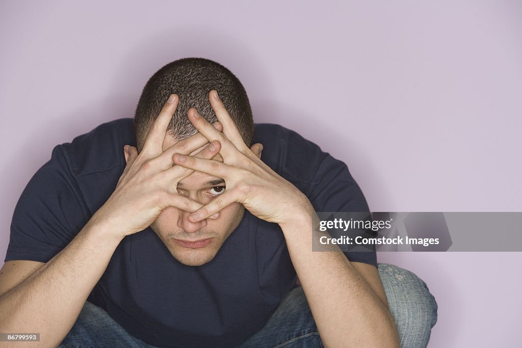 Man peeking through hands