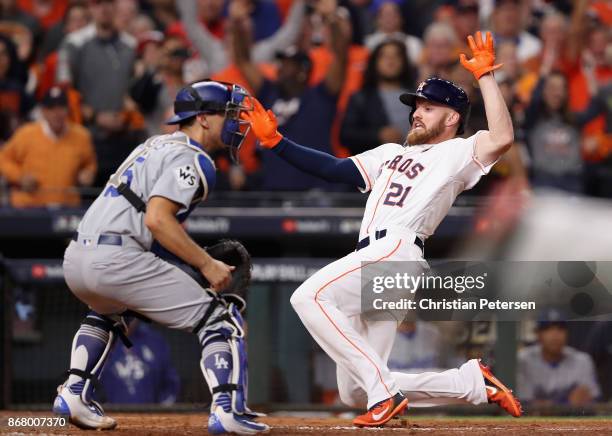 Derek Fisher of the Houston Astros slides in to home plate scoring the game winning run during the tenth inning against Austin Barnes of the Los...