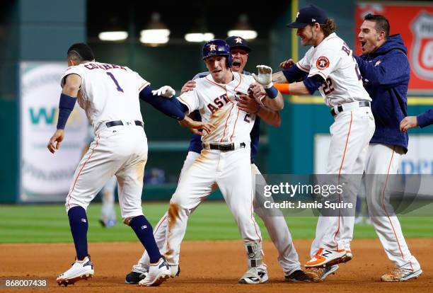 Alex Bregman of the Houston Astros celebrates with teammates after hitting a game-winning single during the tenth inning against the Los Angeles...