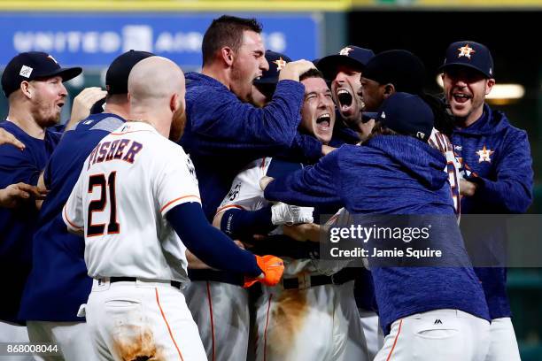 Alex Bregman of the Houston Astros celebrates with teammates after hitting a game-winning single during the tenth inning against the Los Angeles...