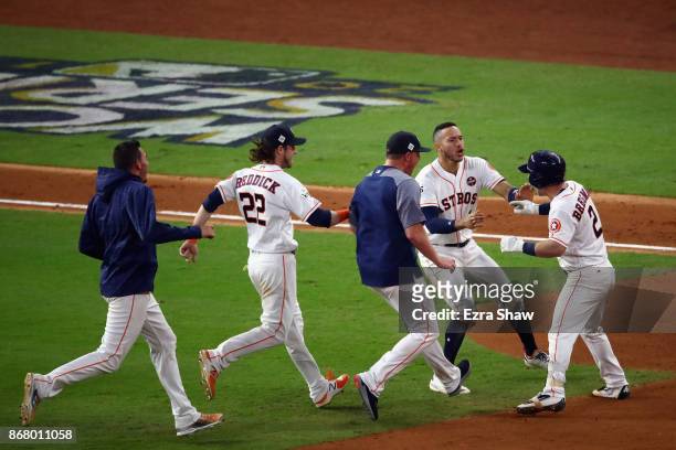 Alex Bregman of the Houston Astros celebrates with teammates after hitting a game-winning single during the tenth inning against the Los Angeles...