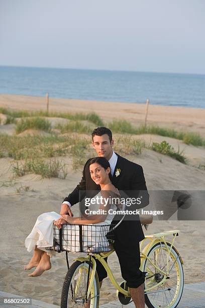 groom riding bicycle with bride in basket - hochzeitspärchen fahrrad stock-fotos und bilder