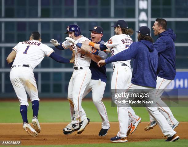 Alex Bregman of the Houston Astros celebrates with teammates after hitting a walk-off single in the 10th inning against the Los Angeles Dodgers in...