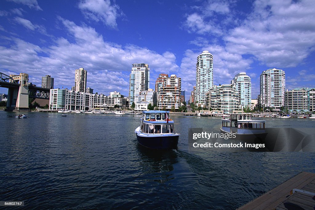 Ferries on river by skyscrapers